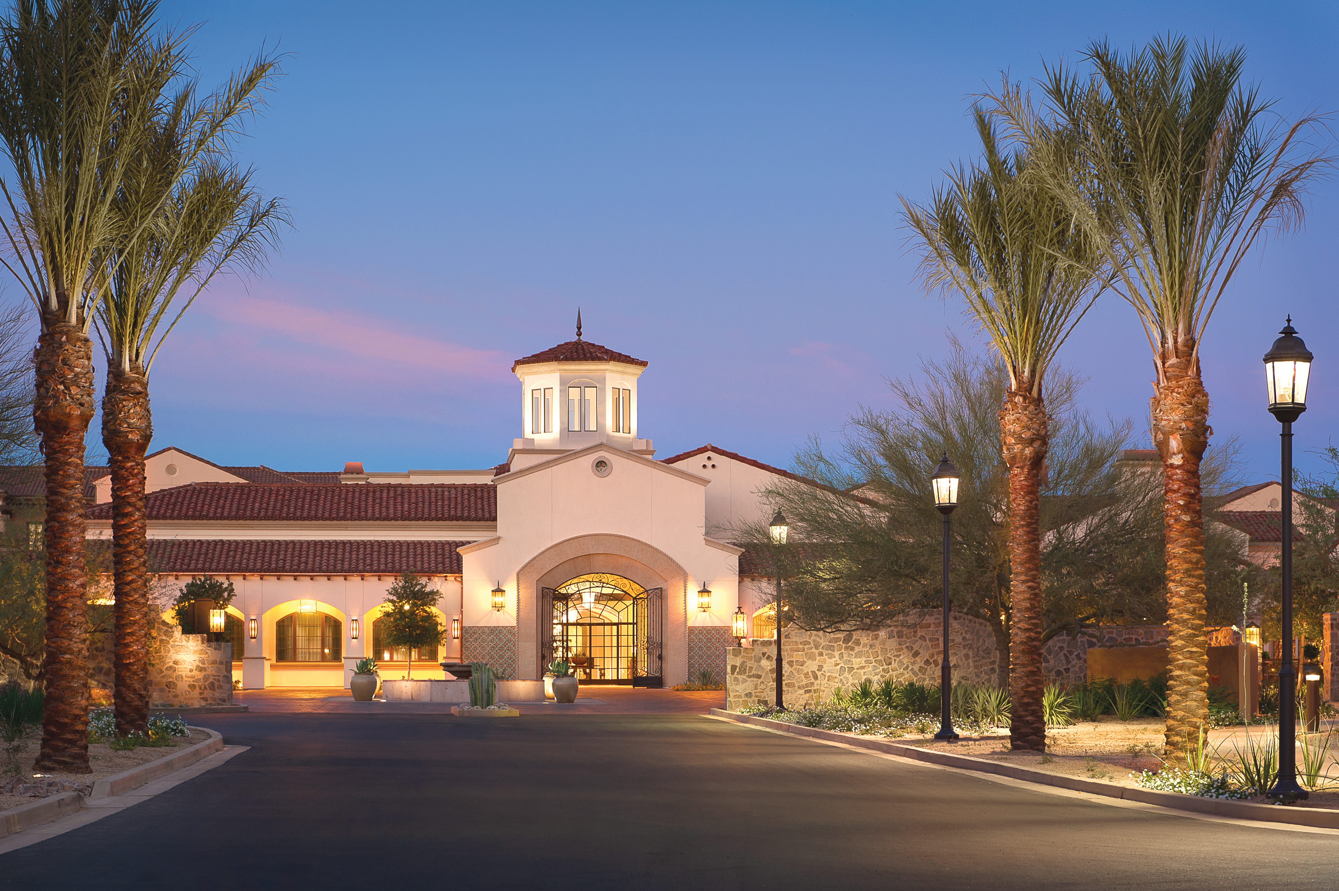 The community entrance at dusk, adorned with palm trees, creates a serene and inviting ambiance.